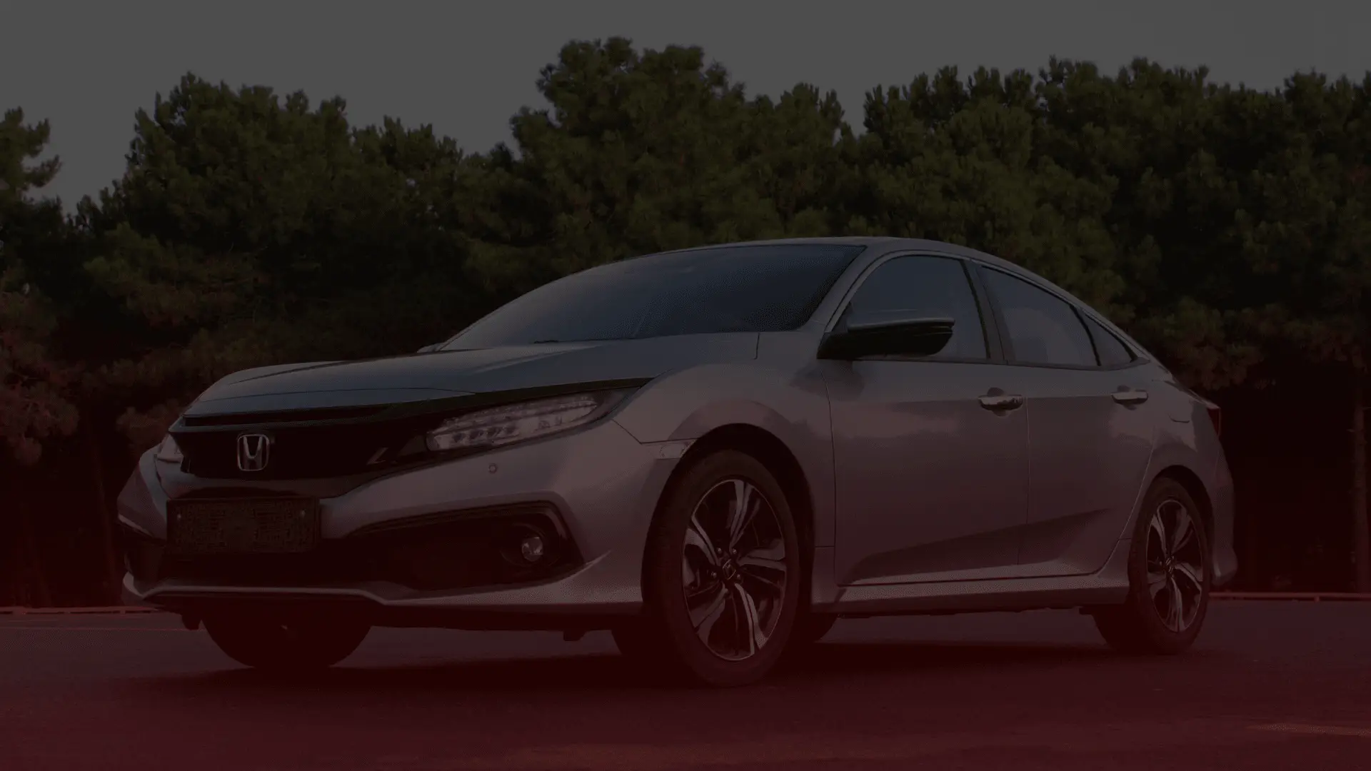 A silver Honda sedan parked on a road with dense green trees in the background. The car, serviced by a top-notch Honda mechanic in Guelph, features black accents and modern headlights, captured in a low-angle shot highlighting its design. EuroMechanic | Brock Road Garage Guelph | Top Reviewed Auto Repair Shop in Guelph | Visit brockroadgarage.ca