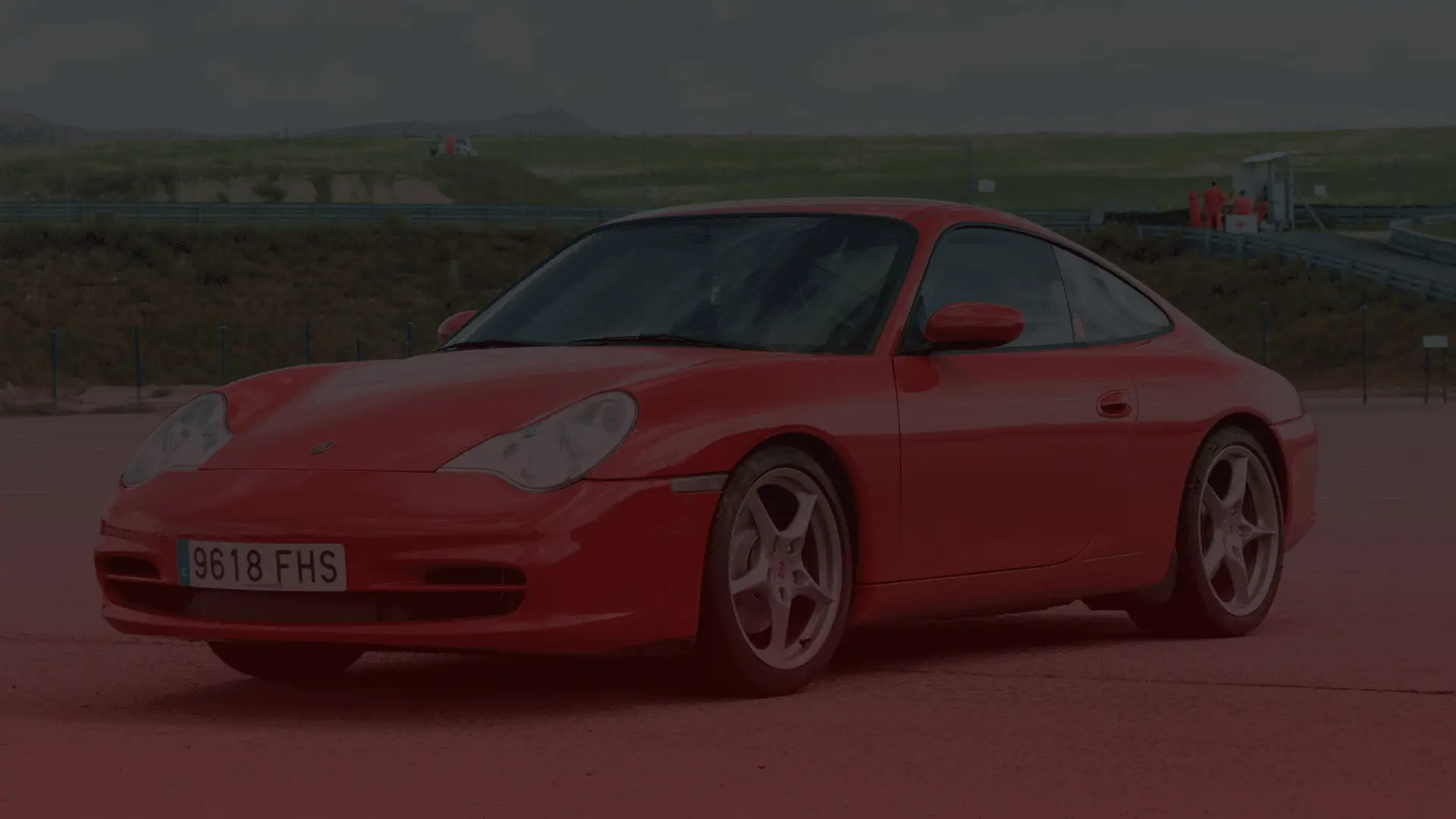 A sleek Porsche sports car is parked on a racetrack, framed by Guelphs lush green hills and a clear sky in the background. EuroMechanic | Brock Road Garage Guelph | Top Reviewed Auto Repair Shop in Guelph | Visit brockroadgarage.ca