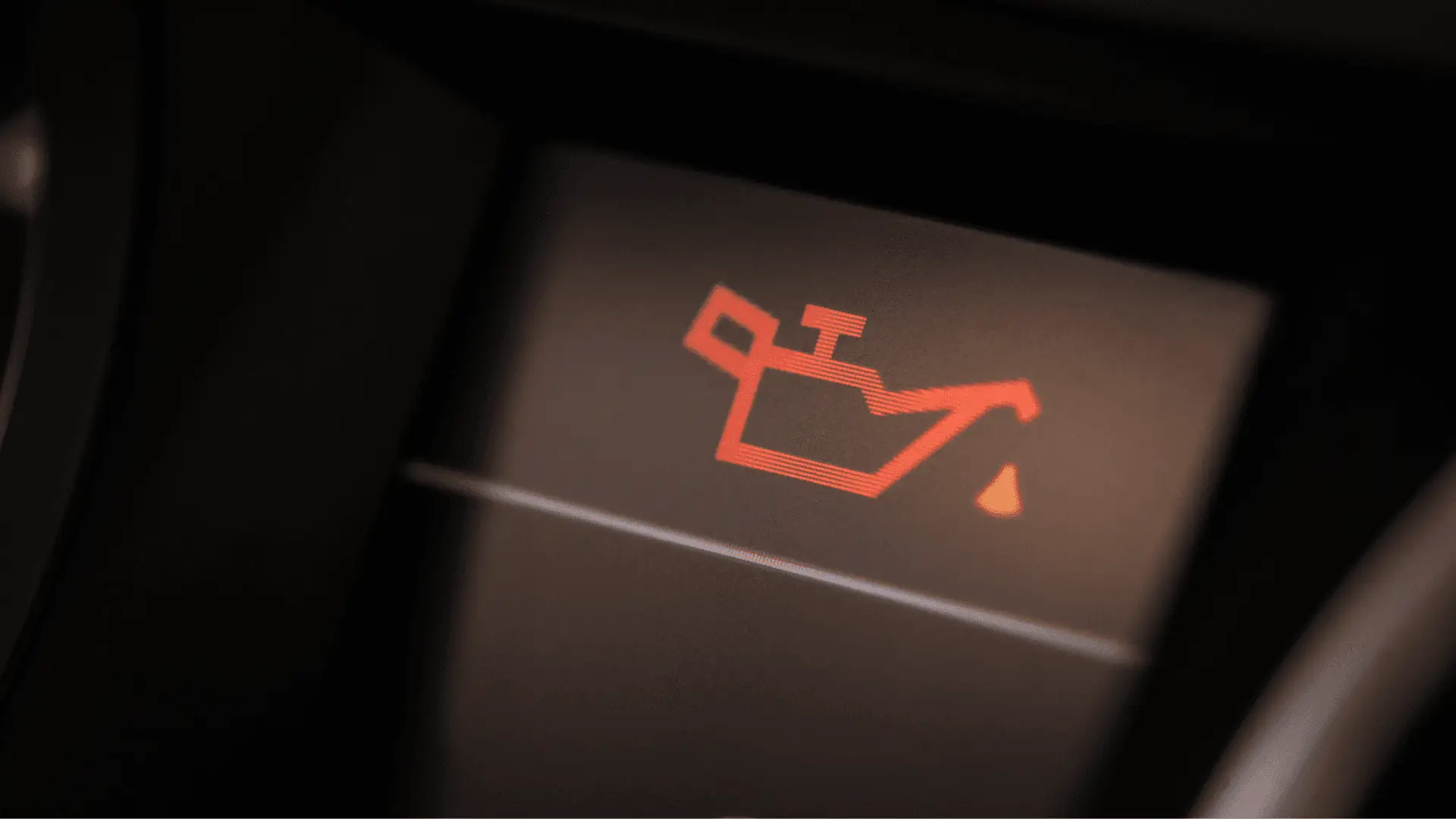 Close-up of a car dashboard light showing a red oil can symbol, indicating low oil or oil pressure warning. The symbol is illuminated on a dark background. EuroMechanic - Brock Road Garage | Top Reviewed Auto Repair Shop in Guelph | Visit EuroMechanic - Brock Road Garage